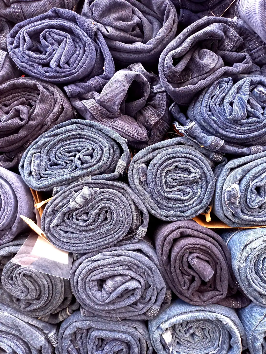 Rolled denim jeans in faded blue shades packed side by side.