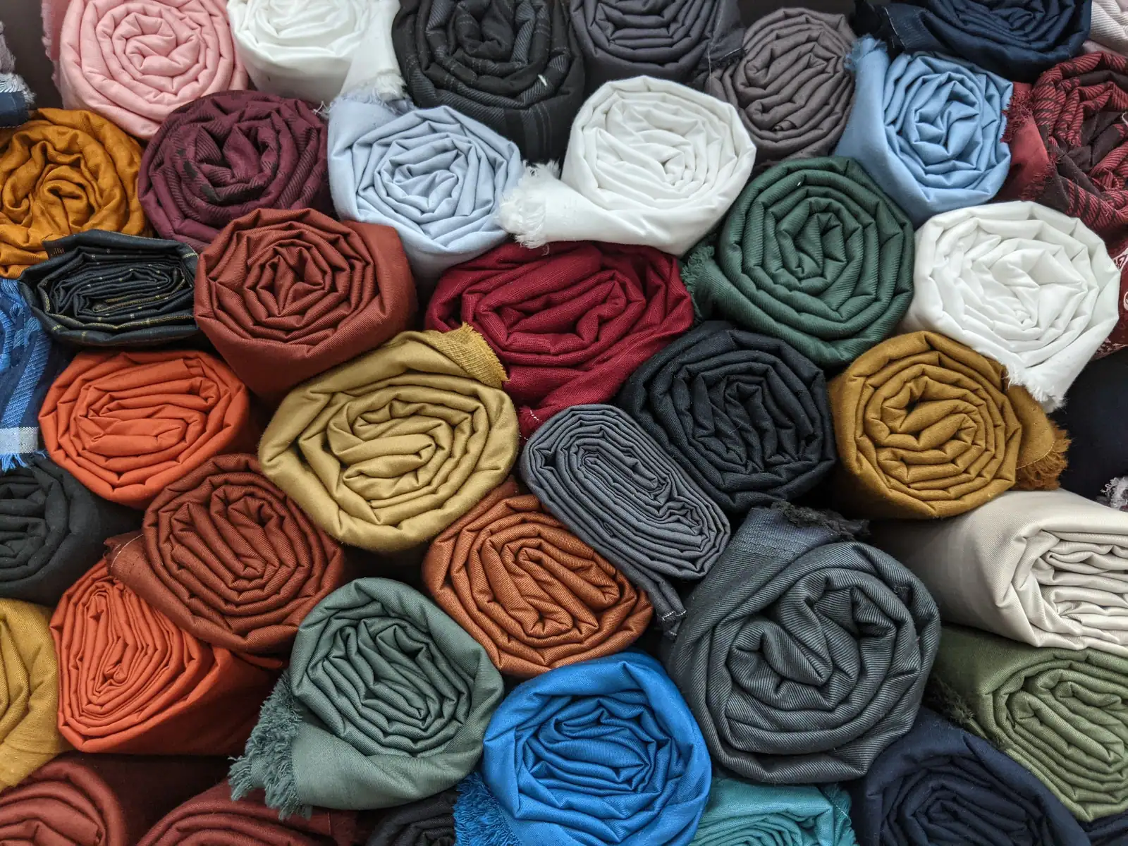 Rolled garments in many colours packed tightly together.