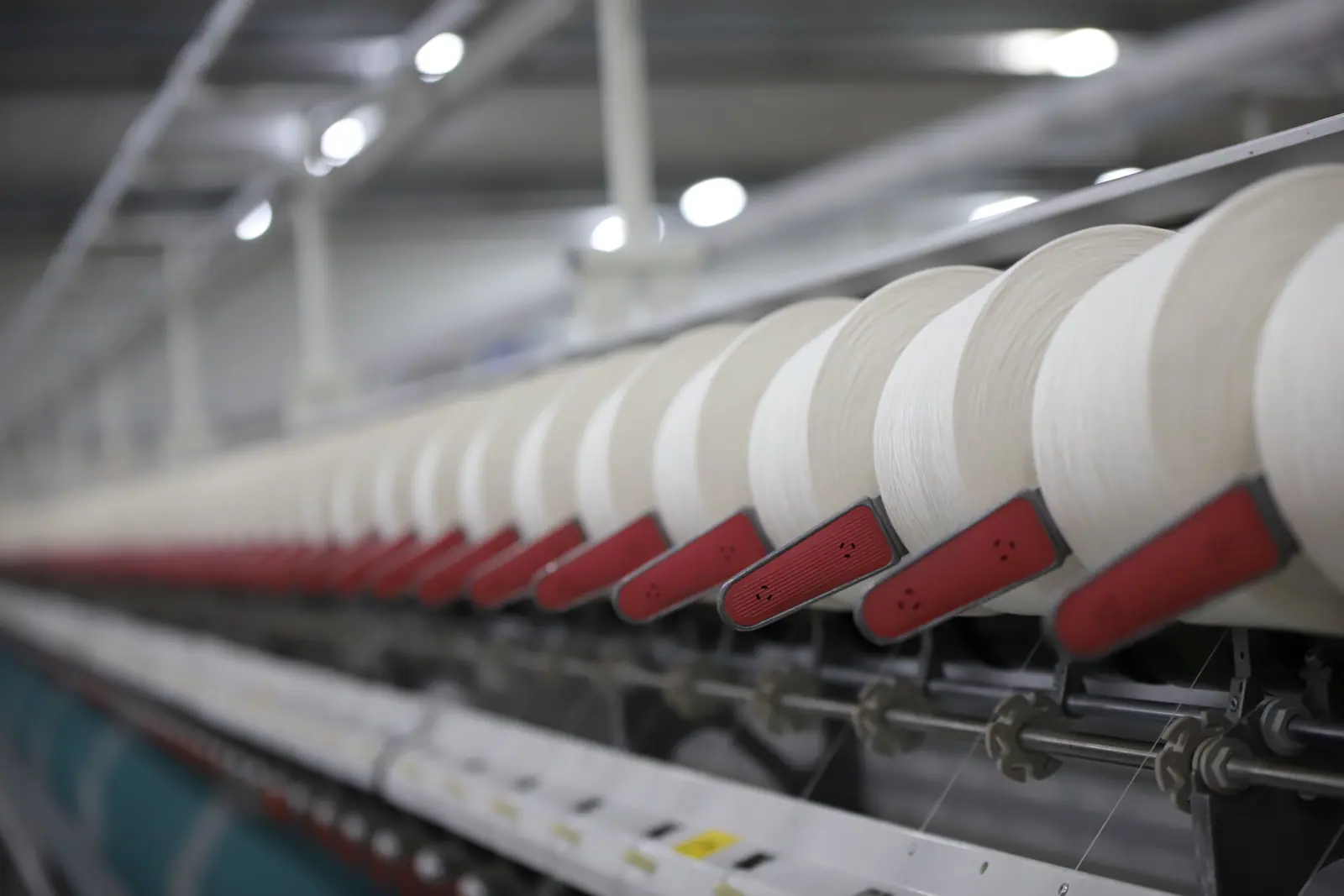 Rows of white thread cones on a textile production line.